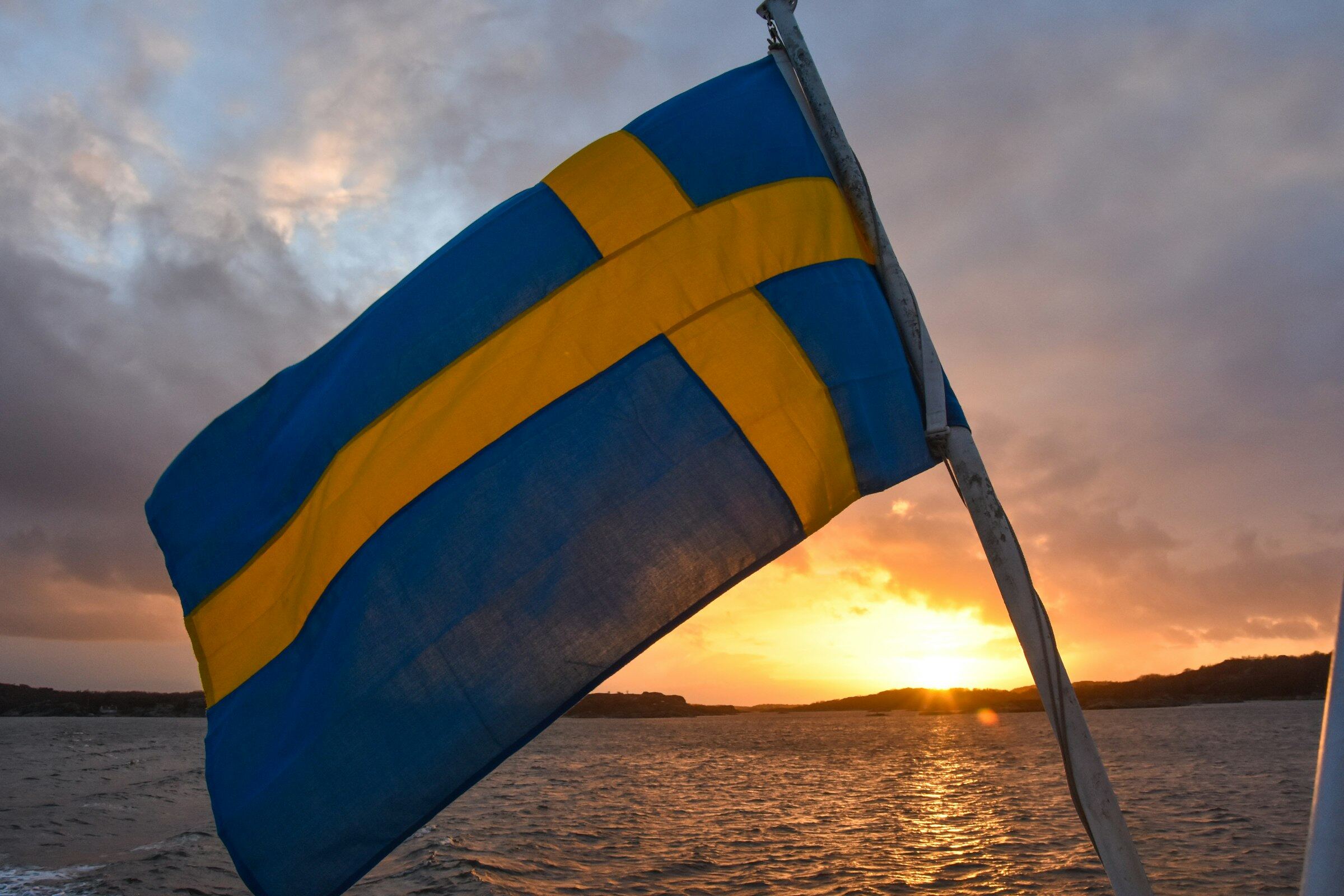 En svensk flagga vajar från en båt i solnedgången